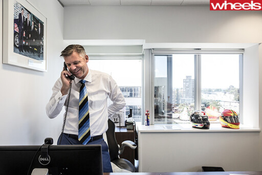 James -Warburton -standing -front -of -desk -on -phone