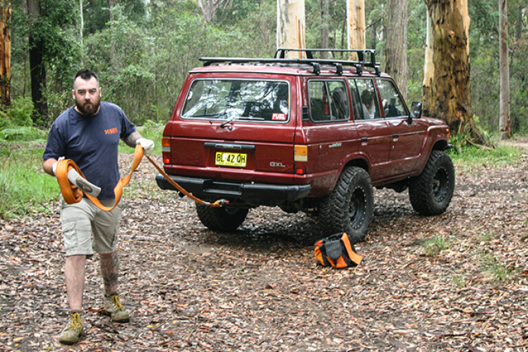 Man attaching rope to rear of 4x4
